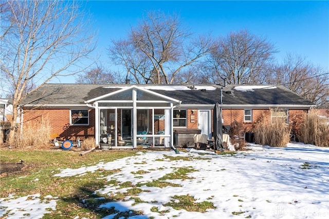 snow covered property with a hot tub and a sunroom