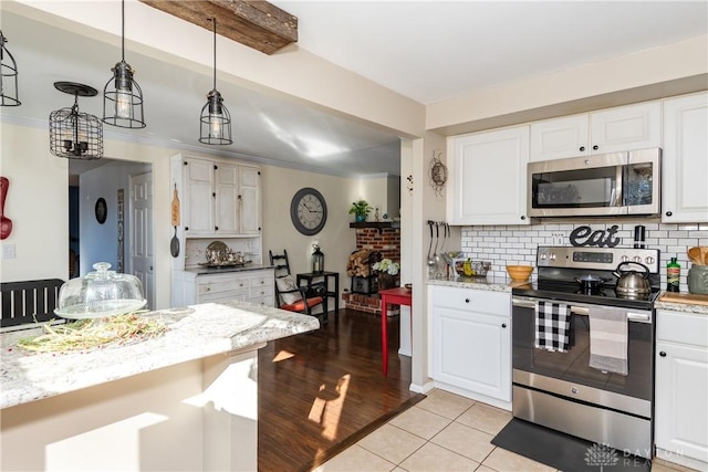 kitchen with white cabinets, decorative backsplash, hanging light fixtures, light tile patterned floors, and stainless steel appliances