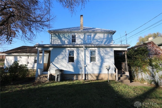 rear view of property with a lawn and a chimney