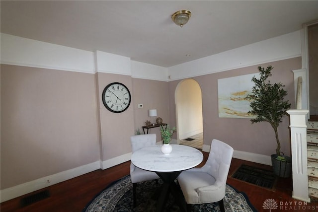 dining room with arched walkways, visible vents, baseboards, and wood finished floors