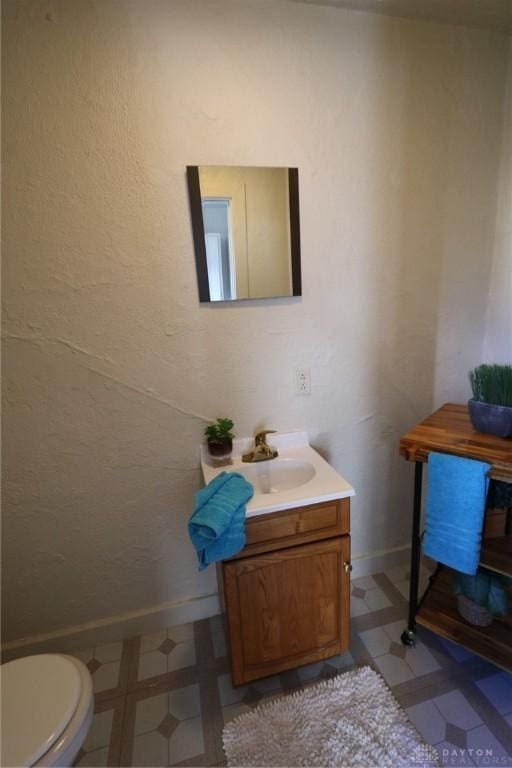 bathroom featuring toilet, tile patterned floors, baseboards, and vanity