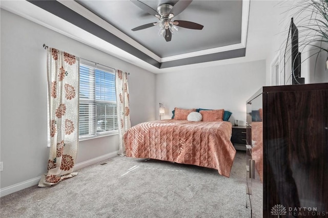 carpeted bedroom with a tray ceiling and ceiling fan