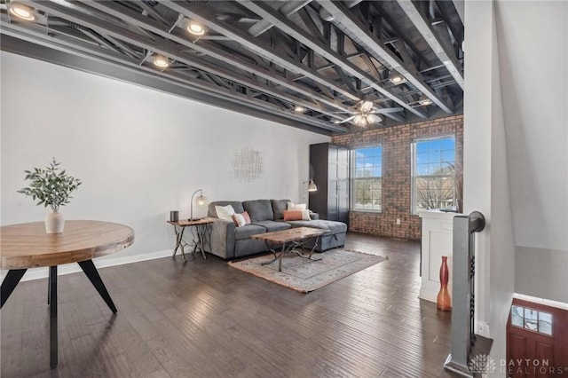 living room featuring dark wood-type flooring and brick wall