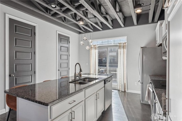 kitchen featuring sink, appliances with stainless steel finishes, an island with sink, dark stone counters, and white cabinets