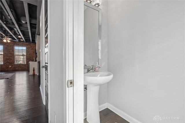 bathroom featuring brick wall and wood-type flooring