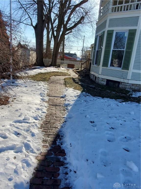 yard covered in snow featuring a balcony