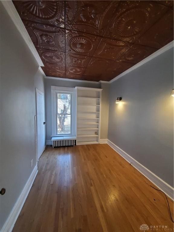 unfurnished room with crown molding, radiator heating unit, and hardwood / wood-style flooring