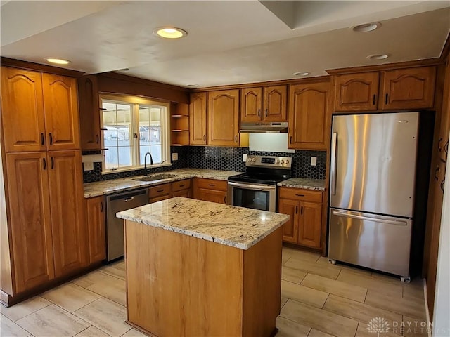 kitchen with sink, decorative backsplash, a center island, stainless steel appliances, and light stone countertops