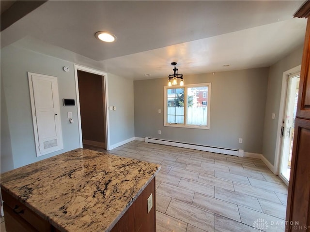 kitchen featuring baseboard heating, light stone countertops, a chandelier, and pendant lighting