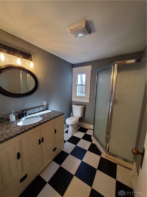 bathroom with vanity, toilet, and a shower with shower door