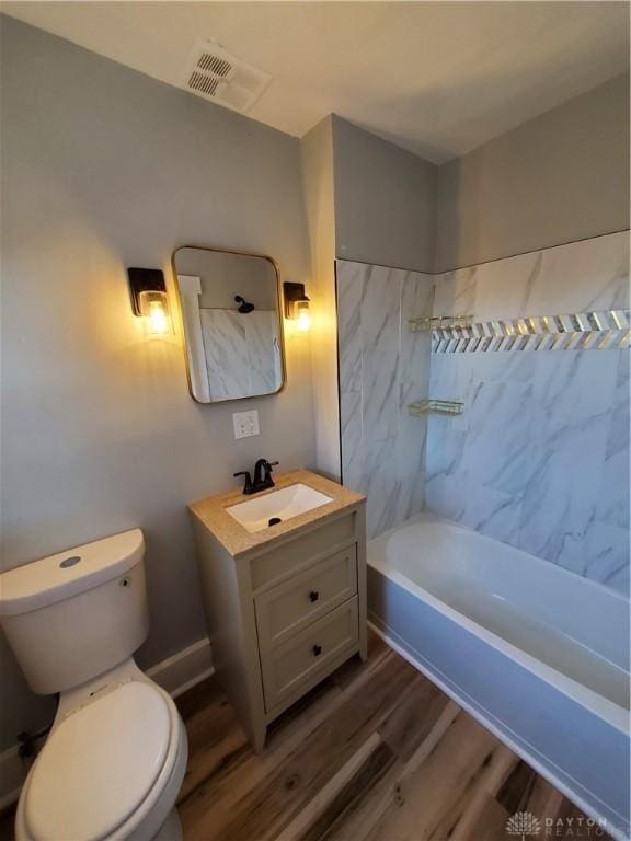 full bathroom with wood-type flooring, tiled shower / bath, vanity, and toilet