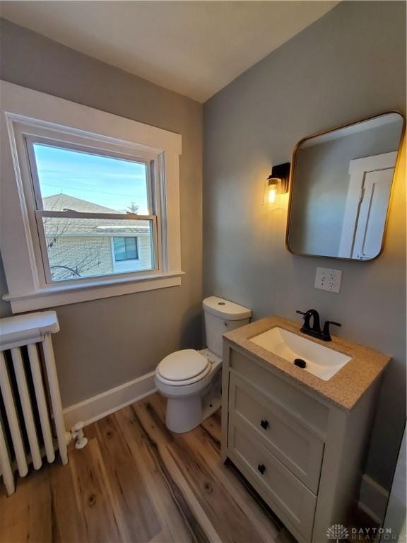 bathroom with vanity, wood-type flooring, radiator, and toilet