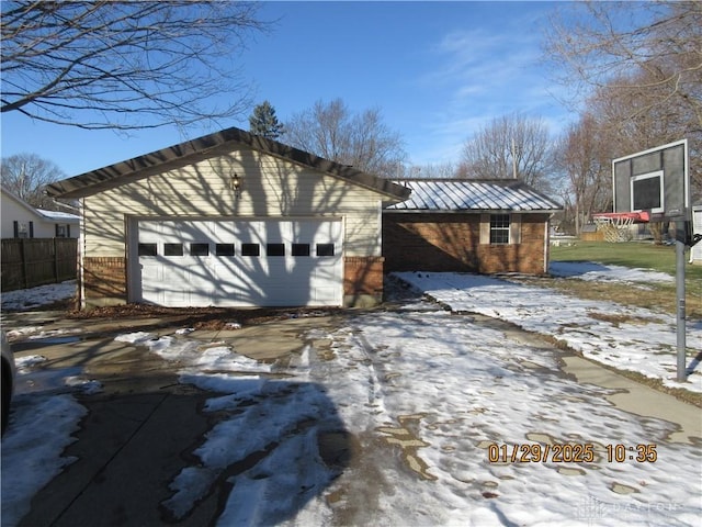 view of snowy exterior with a garage and an outdoor structure