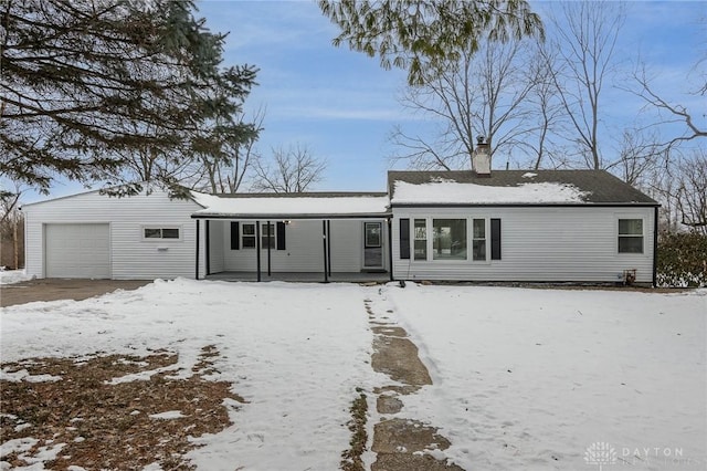 snow covered rear of property with a garage