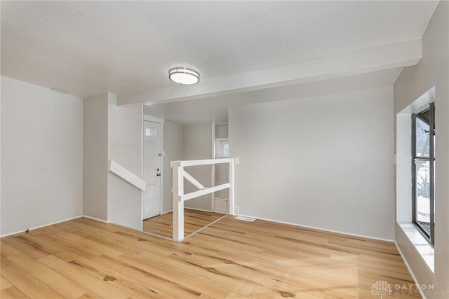 spare room featuring wood-type flooring and beam ceiling