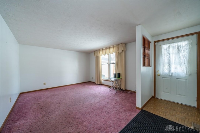 foyer entrance featuring a textured ceiling and baseboards