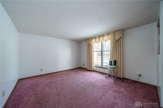 empty room with a textured ceiling, carpet floors, and baseboards