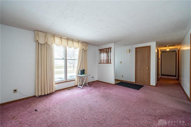 empty room featuring carpet floors, visible vents, a textured ceiling, and baseboards