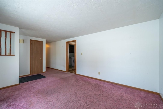 carpeted empty room with washer / dryer, baseboards, and a textured ceiling