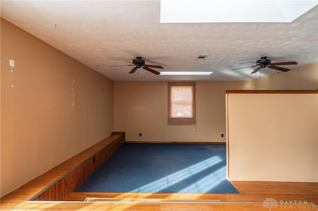 empty room featuring a skylight, visible vents, ceiling fan, and a textured ceiling