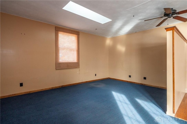 spare room featuring vaulted ceiling with skylight, ceiling fan, and baseboards