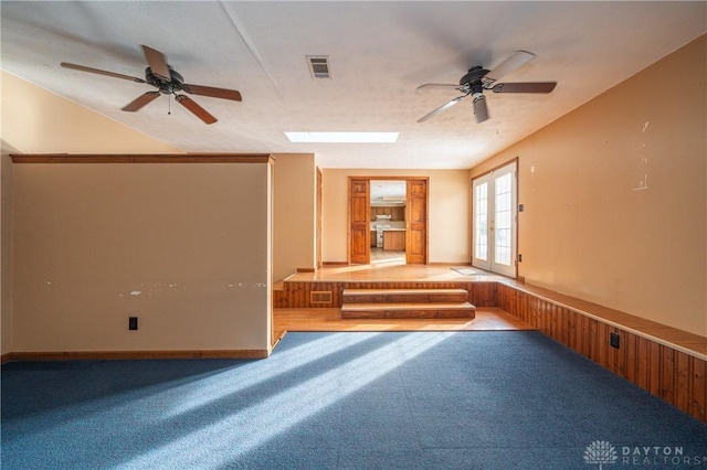 carpeted empty room with a ceiling fan, a skylight, french doors, and visible vents