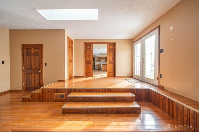 foyer with a skylight, light wood-style floors, and french doors