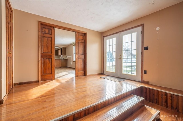 doorway to outside featuring light wood-style floors, baseboards, and french doors