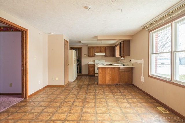 kitchen with visible vents, light countertops, brown cabinetry, white appliances, and a peninsula