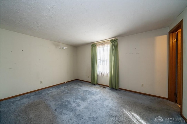 spare room featuring carpet floors, visible vents, a textured ceiling, and baseboards