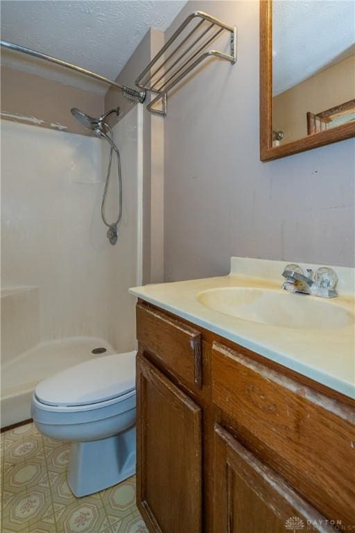 bathroom featuring a textured ceiling, vanity, a shower stall, and toilet