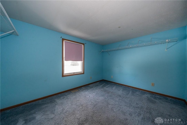 carpeted empty room with a textured ceiling and baseboards