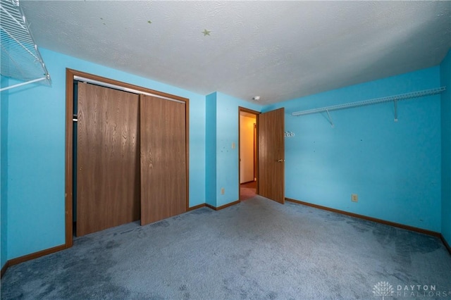 unfurnished bedroom with a closet, carpet flooring, a textured ceiling, and baseboards