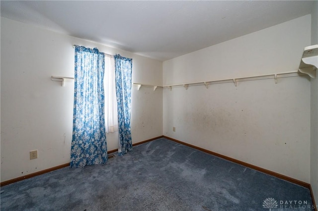 spare room with dark carpet and baseboards