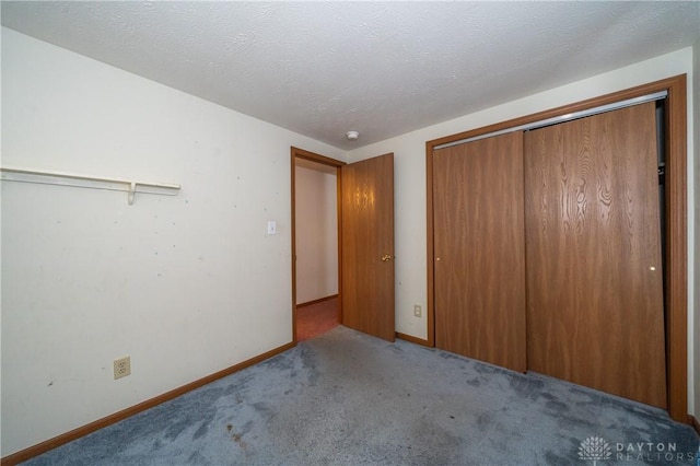 unfurnished bedroom featuring a closet, light carpet, a textured ceiling, and baseboards