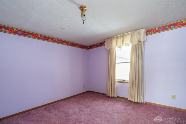 carpeted empty room featuring visible vents, a textured ceiling, and baseboards