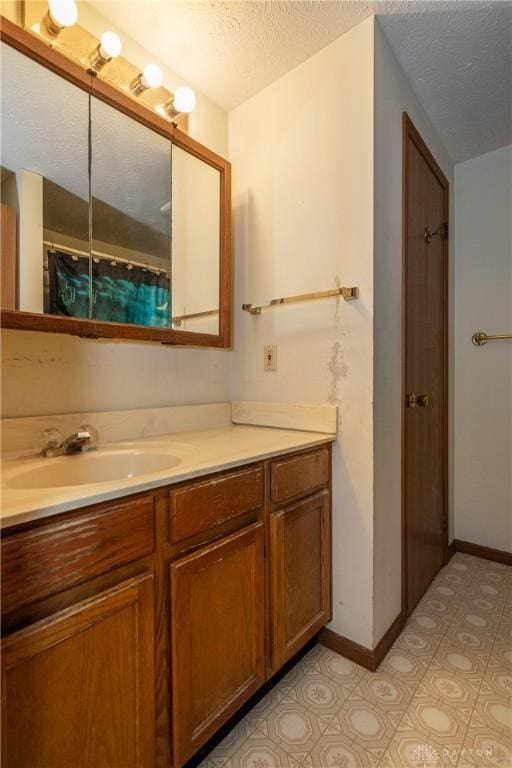 full bathroom featuring baseboards, a textured ceiling, and vanity