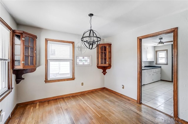 unfurnished dining area with sink, a chandelier, and light hardwood / wood-style floors