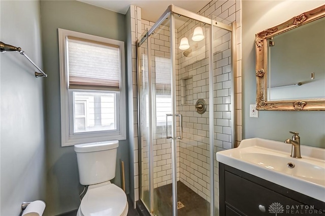 bathroom featuring vanity, a shower with door, and toilet