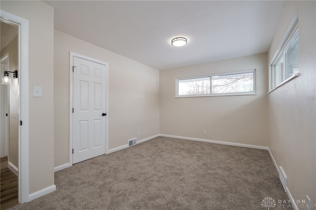 unfurnished room featuring baseboards, visible vents, and carpet flooring