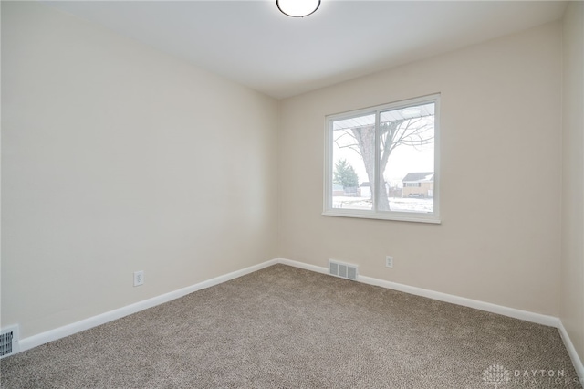 unfurnished room with carpet, visible vents, and baseboards