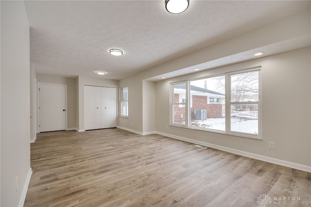 unfurnished room featuring visible vents, a textured ceiling, baseboards, and wood finished floors