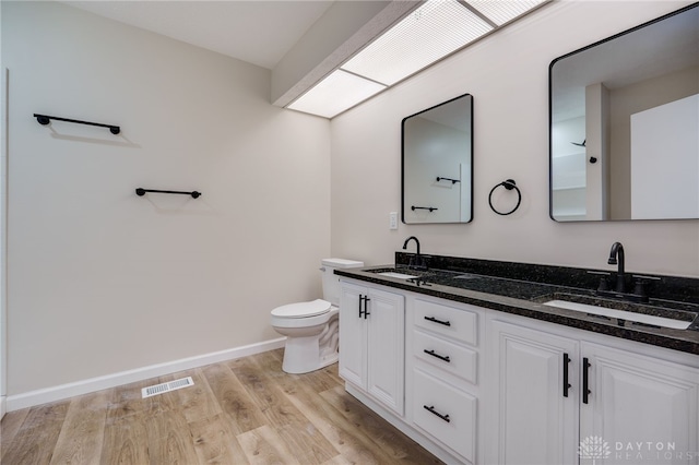 full bathroom featuring toilet, visible vents, a sink, and wood finished floors