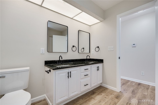 bathroom featuring baseboards, a sink, toilet, and wood finished floors