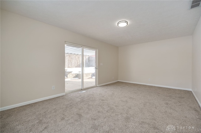 carpeted spare room featuring baseboards, visible vents, and a textured ceiling