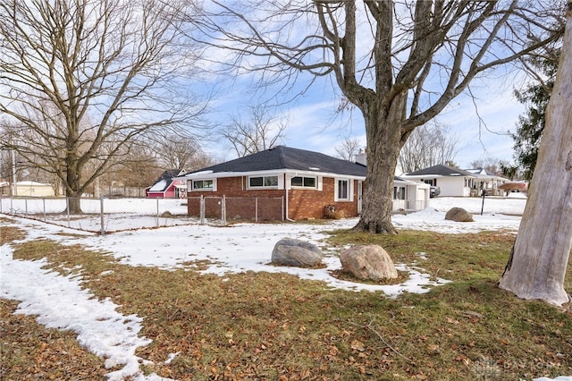 snow covered property featuring a chimney, fence, and brick siding