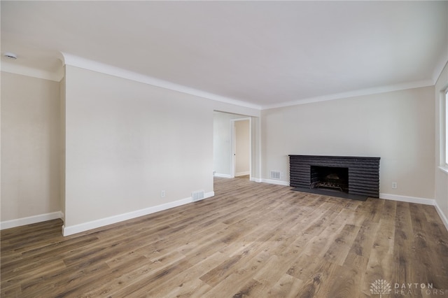 unfurnished living room featuring baseboards, a fireplace, visible vents, and wood finished floors