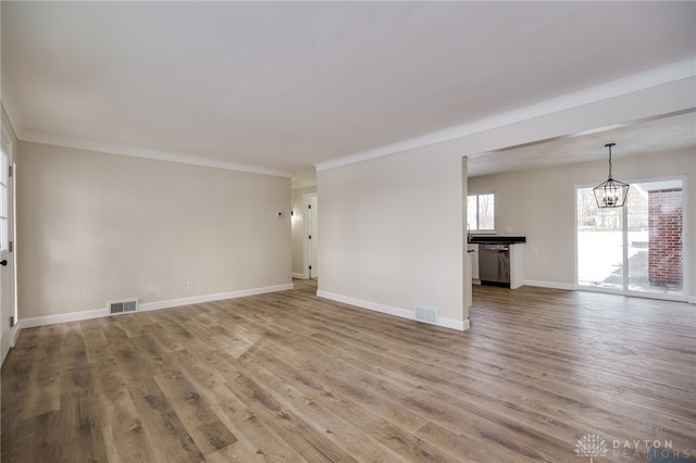 spare room with baseboards, visible vents, an inviting chandelier, and wood finished floors