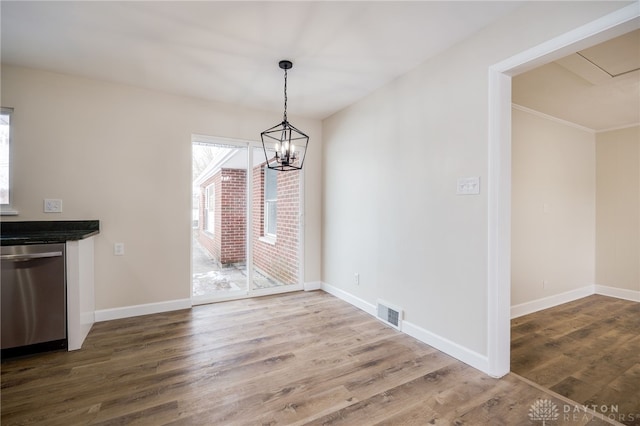 unfurnished dining area featuring an inviting chandelier, visible vents, baseboards, and dark wood-style flooring