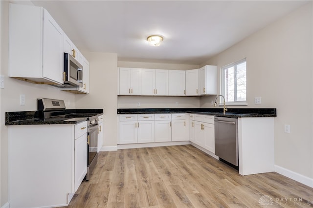 kitchen featuring white cabinets, light wood-style floors, stainless steel appliances, and a sink